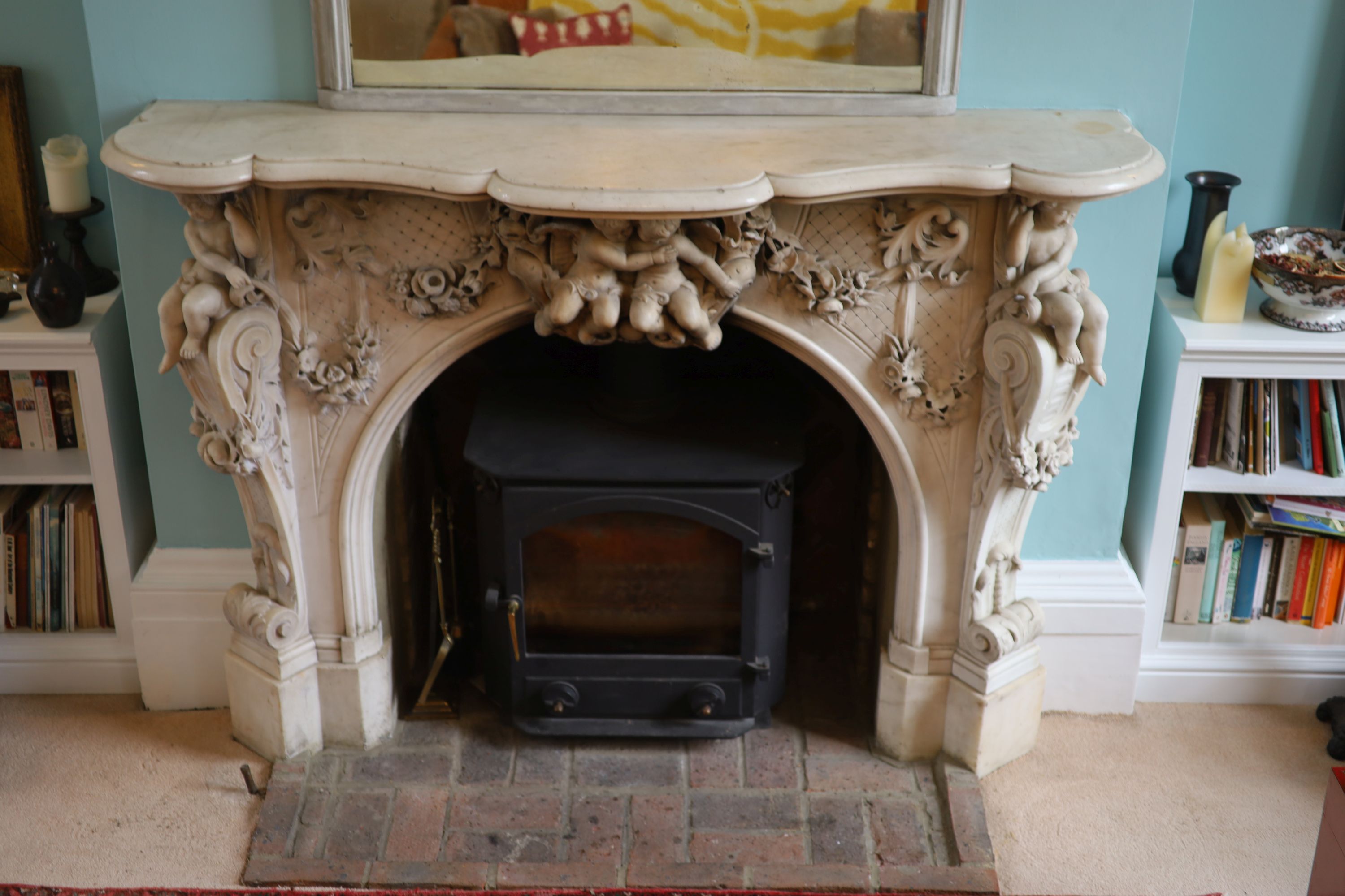 An important mid 19th century Italian white Carrara marble chimney piece, carved in the rococo taste, with seated putti, foliage swags